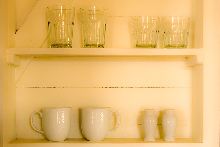 cups and glasses sit on shelves carved into white-painted cottage wall at Mahogany Bay Village on Ambergris Caye in Belize