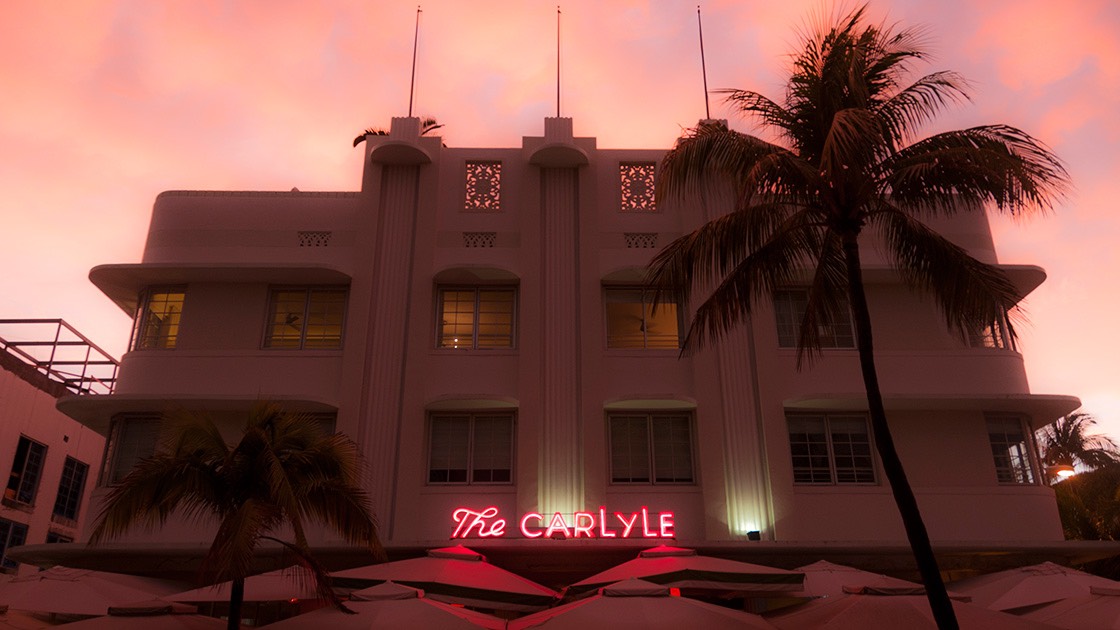The Carlyle on South Beach glows a shaded pink against eerie glow of sunset-lit clouds.