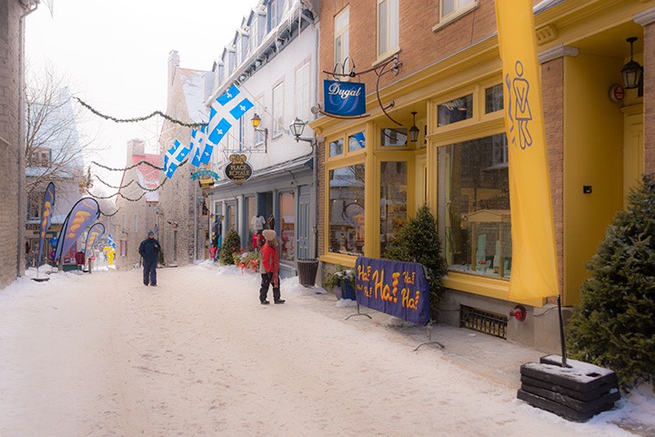 Quebec City shops sit upon a sidewalk coated with recently-fallen snow